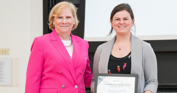 Administrator standing with student receiving a framed award on stage